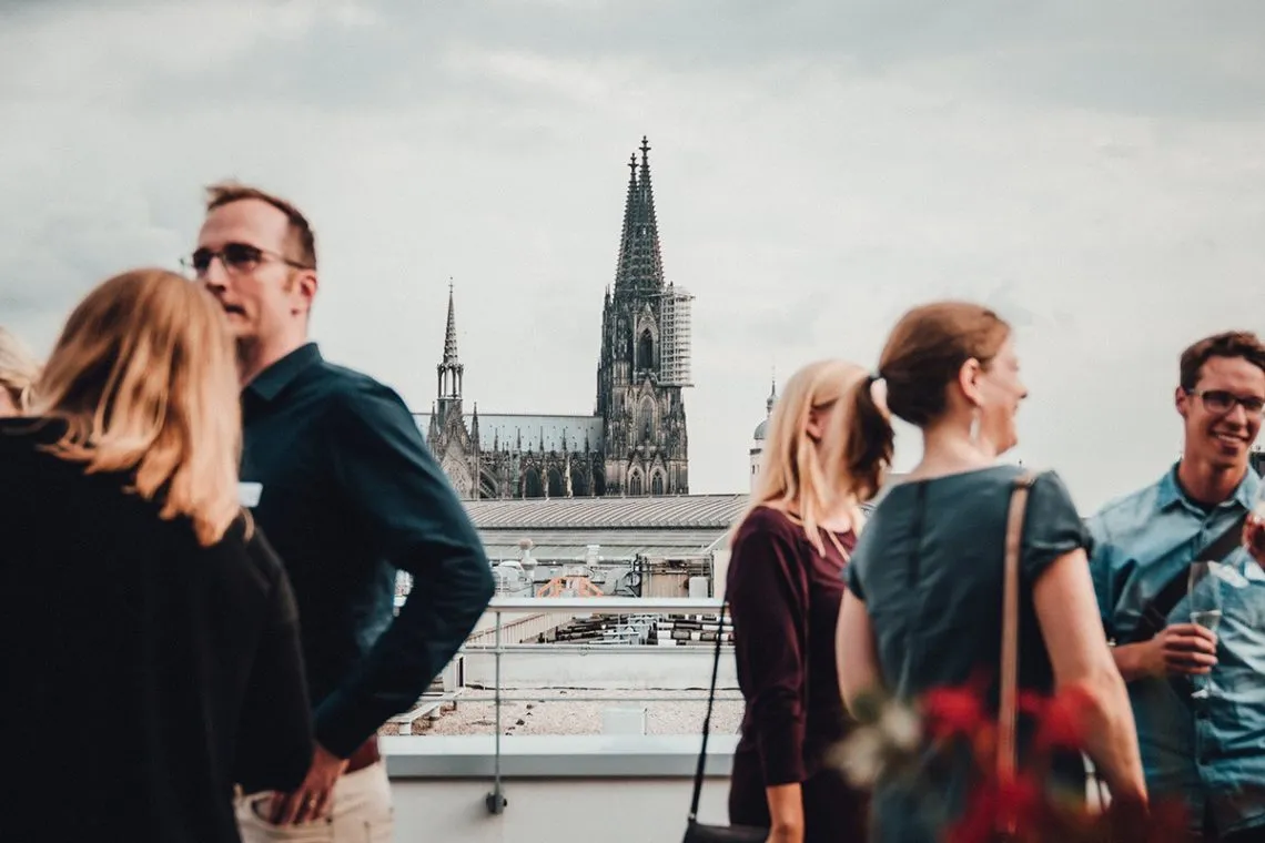Mister Loop fliegt über die Dächer von Köln bei Sonnenuntergang.